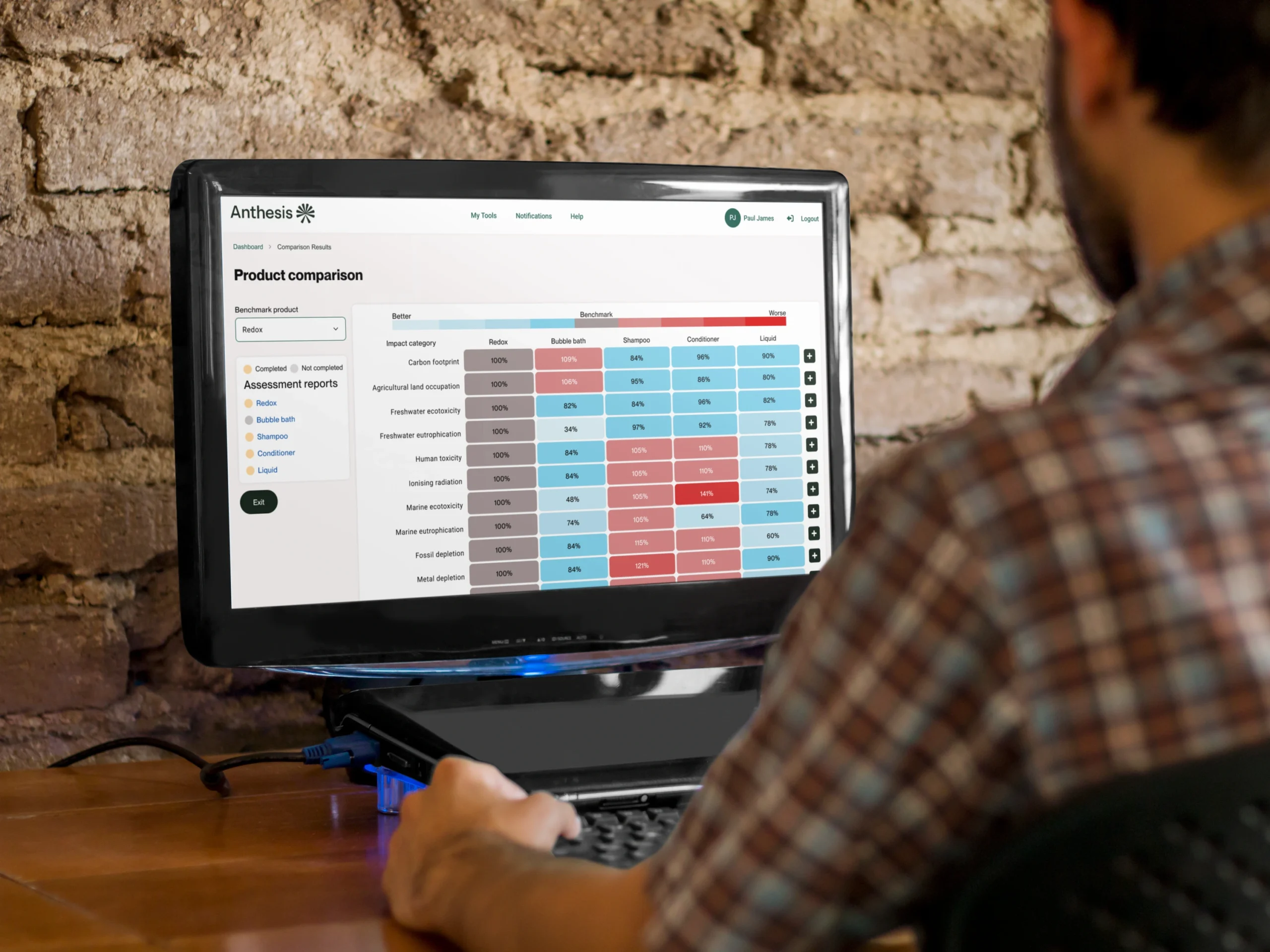 Real-world usage of the product comparison interface displayed on a laptop screen, showing the Anthesis LCA Calculator with benchmark product selection and comparison results in a natural work environment
